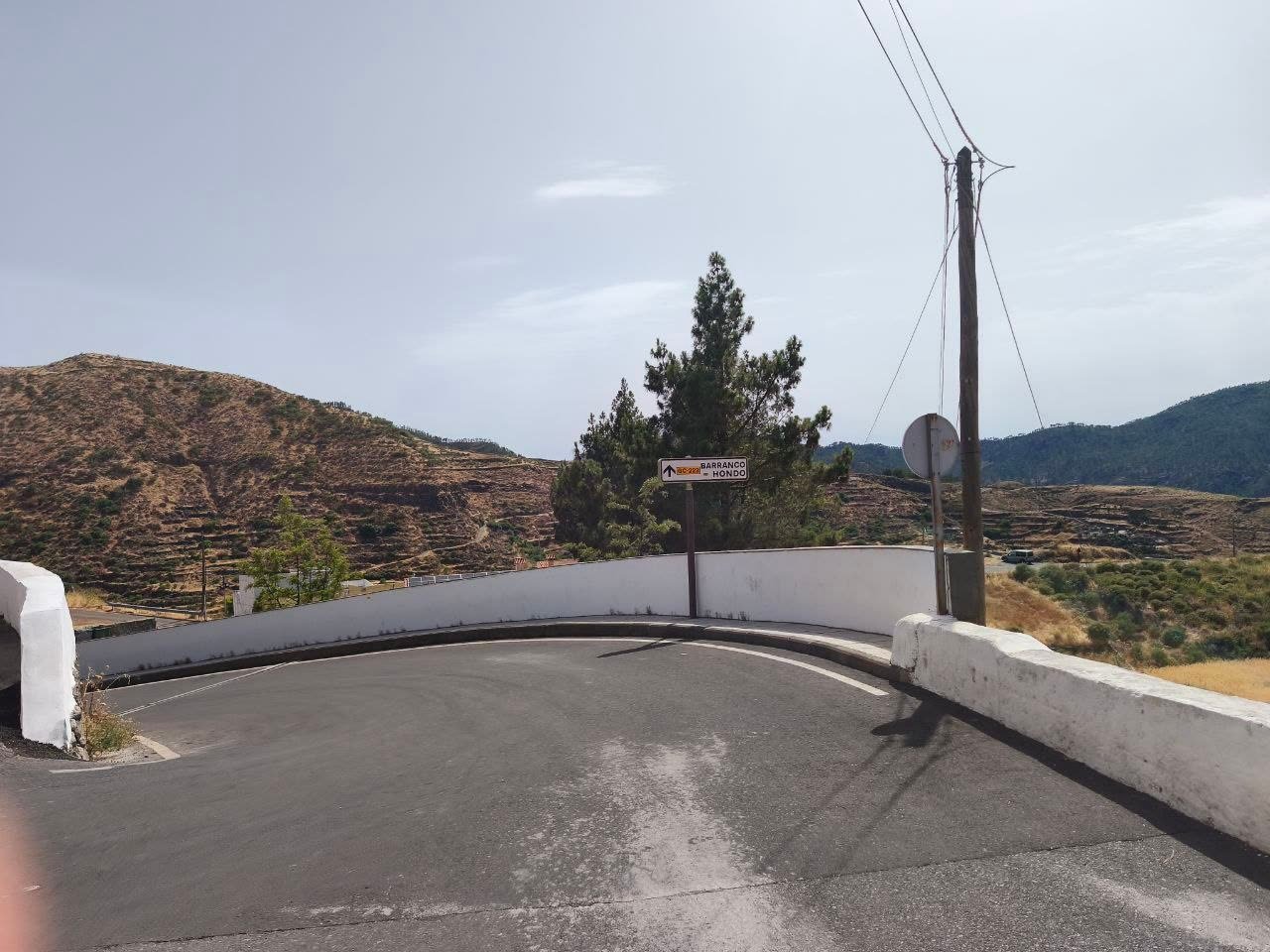 Carretera de acceso al albergue de Juncalillo, Gáldar, con el paisaje de medianías al fondo