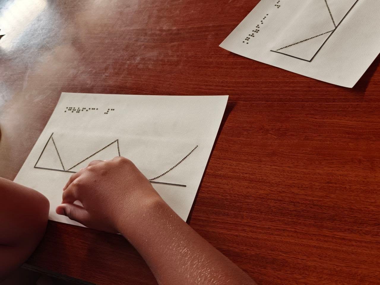 Niños con láminas táctiles en braille descubriendo el concepto de sonificación de datos astronómicos