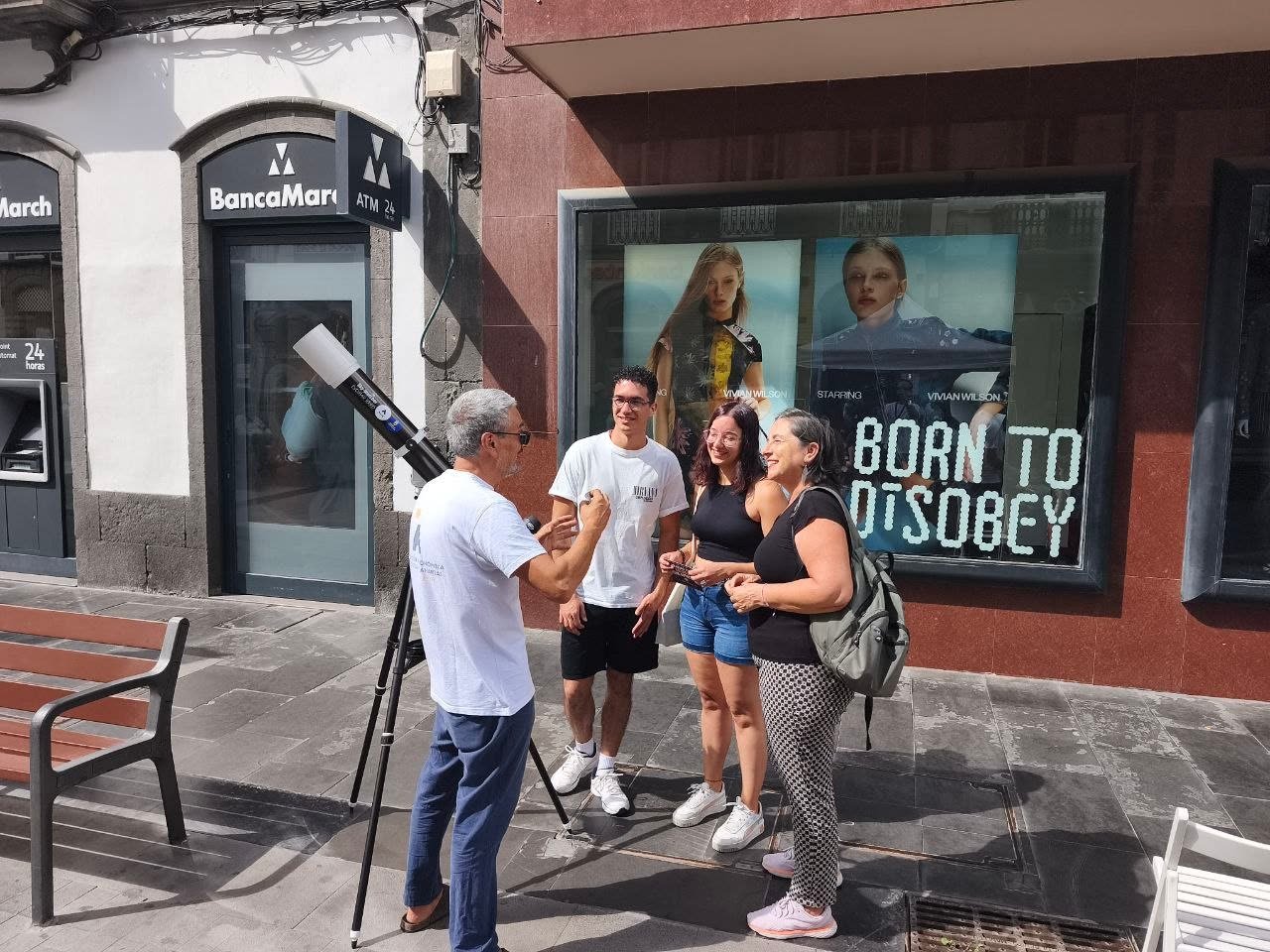 Un miembro de la AAEC explica la campaña contra el DIPG a tres personas junto al telescopio solar